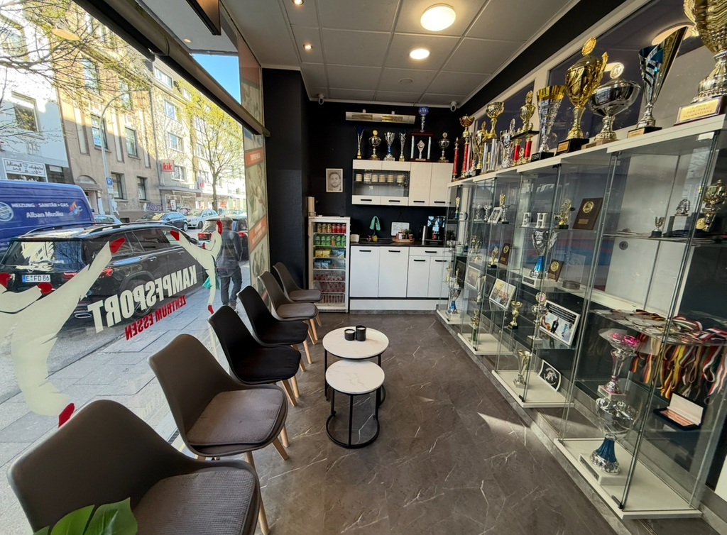 Kampfsport-Studio mit Trophäen, modernen Sitzgelegenheiten und Glasvitrinen.