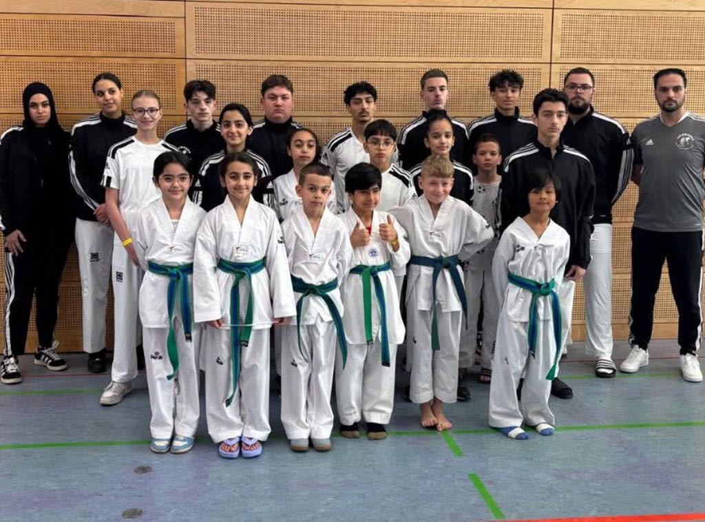 Eine Gruppe von Personen in Sportkleidung posiert in einer Turnhalle.