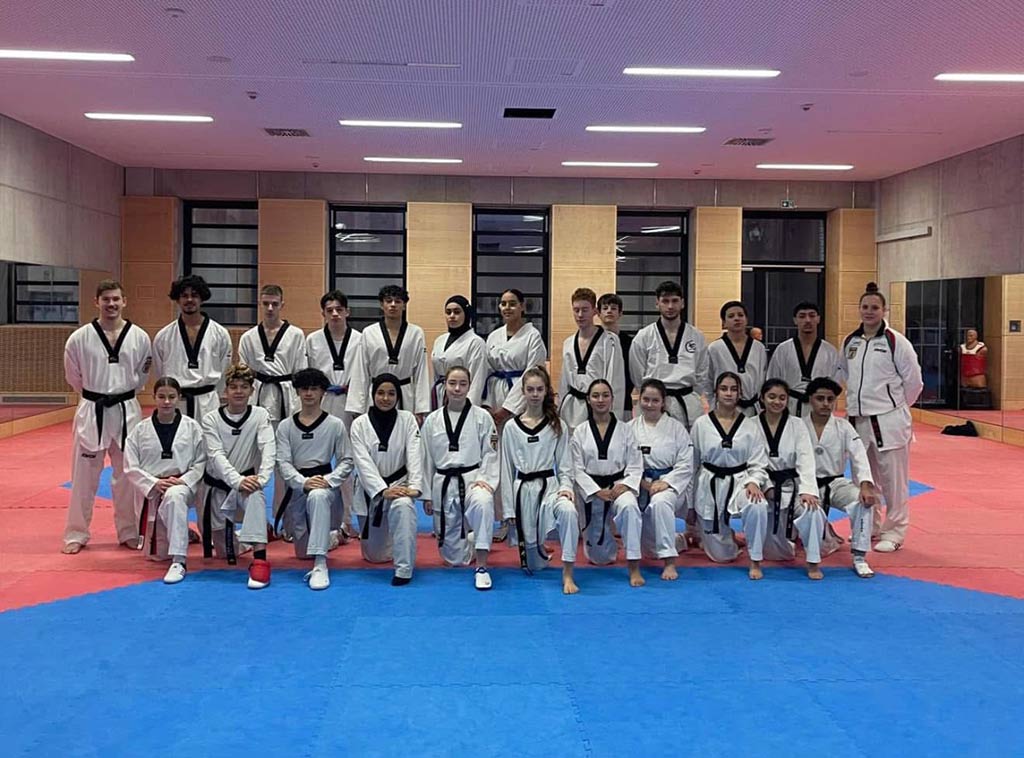 Eine Gruppe von Menschen in Taekwondo-Kleidung posiert in einem Dojang.